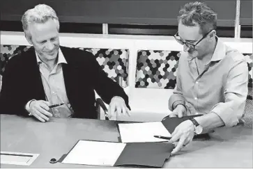  ?? TeleSign ?? DANIEL KURGAN, left, chief of Belgacom Internatio­nal Carrier Services, and Aled Miles, chief of TeleSign Corp., sign an acquisitio­n agreement. TeleSign said it generated more than $100 million in sales last year.