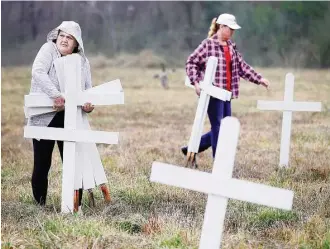  ?? Karen Warren / Houston Chronicle ?? Rebecca Love picks up white crosses that relatives had placed to symbolize the 43 people buried in the Aldine cementery. Grave markers were removed or damaged by workers, they said.