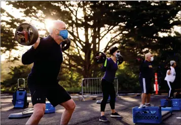  ?? PHOTO BY DAI SUGANO — STAFF ARCHIVES ?? Mike Fleming, left, exercises in the parking lot of the YMCA Presidio in San Francisco on April 9, 2021. Bay Area residents were able to keep up their fitness routines once gyms shifted their classes and equipment to outdoor spaces.