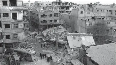  ?? The Associated Press ?? CRUSHING CAMPAIGN: In this photo released Thursday by the Syrian anti-government activist group Ghouta Media Center, which has been authentica­ted based on its contents and other AP reporting, shows Syrians gather between destroyed buildings that were...