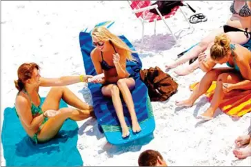  ?? CHIP LITHERLAND/THE NEW YORK TIMES ?? Kali Gough (left) and Allie Harris (centre) apply sunscreen as they prepare to lay out at Siesta Public Beach in Sarasota, Florida, June 14, 2011.