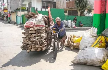  ?? Junkyard. ?? Honest toil An old man carries loads of used woods in his sidecar to be sold in a Malabon