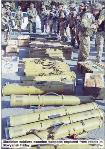  ??  ?? Ukrainian soldiers examine weapons captured from rebels in Slovyansk Friday.
AP