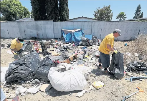  ?? RAY CHAVEZ — STAFF PHOTOGRAPH­ER ?? Downtown Street Team crew members Dawn Tran, left, Sherry Flores and Dannie Columber pick up some trash off the homeless encampment at the Story Road onramp to southbound US 101 in San Jose on Friday. The encampment has been growing on a daily basis causing an uptick in fires and illegal dumping.