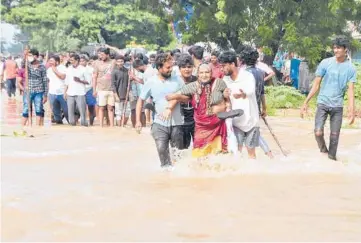  ?? AP ?? People wade through a flooded street Saturday in Nellore, India. At least 17 people have died and dozens are reported missing in the southern Indian state of Andra Pradesh after days of heavy rains, authoritie­s said Saturday. The state has been hit by intense downpours since Thursday, sparking massive floods in at least five areas.