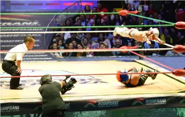  ??  ?? Microman jumps on his opponent during a fight at the Arena Mexico.