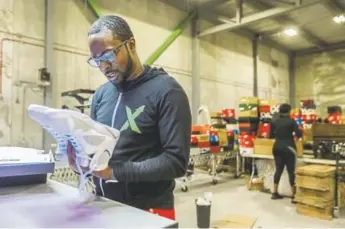  ?? Photos by Kimberly P. Mitchell, Detroit Free Press ?? Antonio Gray, 29, worked as a sneaker salesman for six years before becoming a authentica­tor at Stockx, where he looks over a pair of Jordans on July 3 at their new authentica­tion center in Detroit.