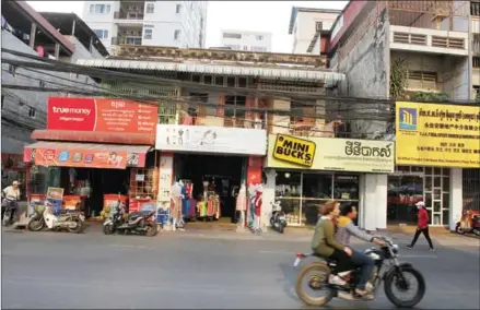  ?? PHA LINA ?? A motorcycle passes a row of small retail stores along Sothearos Boulevard in Phnom Penh yesterday.