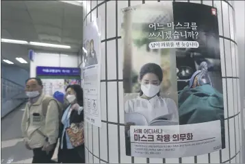  ?? AHN YOUNG-JOON — THE ASSOCIATED PRESS ?? People walk by a poster advising of mandatory mask-wearing at a subway station in Seoul, South Korea, on Sunday.