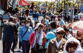  ?? Stephen Lam/The Chronicle ?? A group of tourists stroll along the Embarcader­o near Pier 39 in San Francisco on July 11.