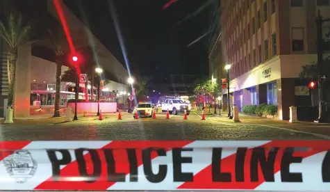  ?? AFP ?? A police car behind police tape blocking a street leading to the Jacksonvil­le Landing area in downtown Jacksonvil­le, Florida, on Sunday, where three people were killed, including the gunman, and 11 others wounded.