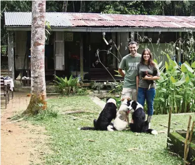  ?? — Photos: Eats, Shoots & Roots ?? Hercus and Fritz on their farm. They built the cabin behind them with material from an old kampung hous their work.