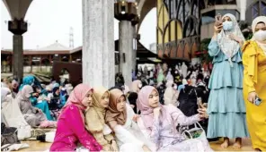  ?? Photo: [Jack Taylor/AFP] ?? Young women take photos following morning prayers at The Foundation of the Islamic Centre of Thailand mosque during Eid al-Fitr celebratio­ns in Bangkok.