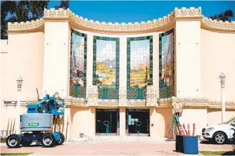  ?? KRISTIAN CARREON ?? Workers finish the exterior of the San Diego Automotive Museum on Monday. The $715,000 project includes re-created murals representi­ng California’s commerce, scenic beauty, agricultur­e and industry.