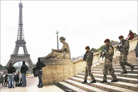  ?? Emilio Morenatti/Associated Press ?? Army soldiers patrol near Trocadero plaza with the Eiffel Tower in the background on Saturday in Paris.