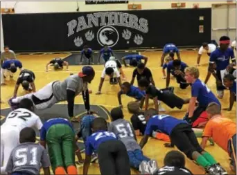  ?? DIGITAL FIRST MEDIA ?? Media native and Strath Haven grad Steven Johnson, center left, shows campers proper push-up form during the second Faith Motivated Foundation football camp held at his alma mater in Nether Providence.