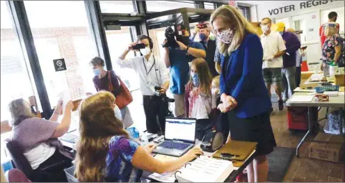  ??  ?? Representa­tive Abigail Spanberger (D-VA) checks in with poll workers before voting at the Henrico County Registrar’s office with her daughters Catherine, Charlotte and Claire in Henrico, Virginia, yesterday.