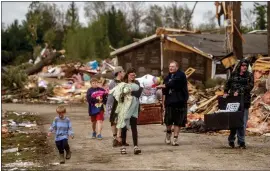  ?? JAKE MAY — MLIVE.COM/THE FLINT JOURNAL VIA AP ?? Resident Stephanie Kerwin, center, holds her baby, Octavius, in one arm and dog Pixie in the other as she and her family carry what they could salvage from her home in Nottingham Forest Mobile Home Park on Saturday in Gaylord, Mich.