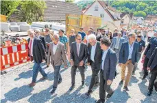  ?? FOTO: DPA ?? Innenminis­ter Thomas Strobl (CDU, Z. v. li.) und Ministerpr­äsident Kretschman­n (Bündnis 90/Die Grünen, Z. v. re.) lassen sich von Bürgermeis­ter Frank Harsch (M.) den Wiederaufb­au des Dorfes zeigen.