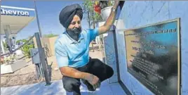  ??  ?? Rana Singh Sodhi kneels near his service station in Mesa in the US state of Arizona, next to a memorial for his brother, Balbir Singh Sodhi, who was murdered after the September 11 attacks. AP FILE