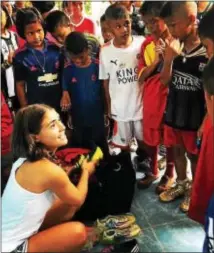  ?? COURTESY OF COLLEEN WILLIAMS ?? Vice president of SistaSocce­r Julie Oberholtze­r, left, hands out soccer equipment to kids during a trip to Thailand.