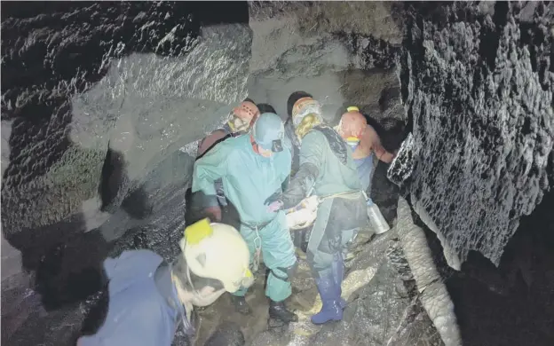  ?? ?? ↑ Rescuers carry the injured man on a stretcher through caves in the Brecon Beacons after a 54-hour rescue operation