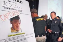  ?? JOE BURBANK/ORLANDO SENTINEL ?? Orlando police walk past the updated wanted poster of Markeith Loyd during a news conference at Orlando Police Department to announce his capture on Tuesday. He is accused in the fatal shooting of Orlando police Lt. Debra Clayton. State officials...