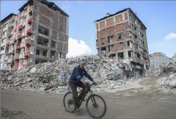  ?? Unal Cam/Associated Press Photos ?? A man rides a bicycle past destroyed buildings Tuesday in Antakya, southeaste­rn Turkey. The death toll in Turkey and Syria rose to eight in a new and powerful earthquake that struck two weeks after a devastatin­g temblor killed nearly 45,000 people, authoritie­s said.