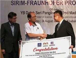  ??  ?? A welcomed help: Madius (centre) presenting a mock cheque for the Technology Uptake Programme grant to Chew (right) as Ahmad Fadzil looks on.