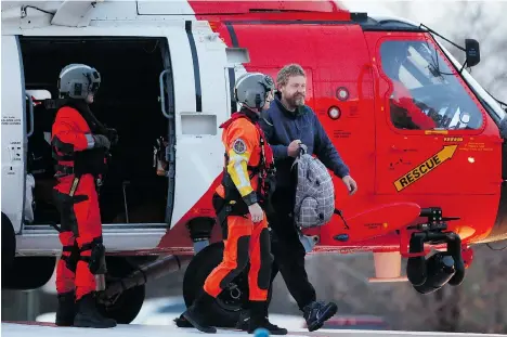  ?? STEVE EARLEY/THE VIRGINIAN-PILOT/THE ASSOCIATED PRESS ?? Louis Jordan, right, walks from the U.S. Coast Guard helicopter to the Sentara Norfolk General Hospital in Norfolk, Va., after being found off the North Carolina coast on Thursday. His family says he sailed out of a marina in Conway, S.C., on Jan. 23,...