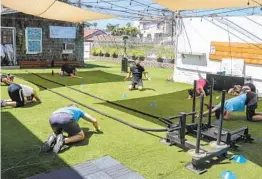  ?? EDUARDO CONTRERAS U-T ?? Michael Hamanaka (center), owner of The Movement Warehouse in Pacific Beach, works outside with clients after new COVID-19 restrictio­ns.