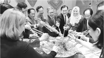  ??  ?? Mustapa (centre) with guests tossing ‘Yee Sang’ after the Chinese New Year networking session in Kuala Lumpur. — Bernama photo