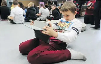  ??  ?? Nine-year-old Layne Curtis uses an augmented reality program on a tablet.