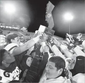  ?? Steve Yeater Associated Press ?? ST. JOHN BOSCO players hoist the state championsh­ip trophy after beating De La Salle, 56-33, in the Open Division final Saturday at Sacramento State behind 357 yards rushing.