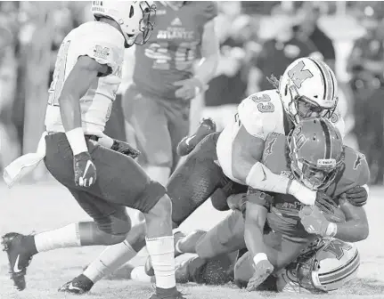  ?? JENNIFER LETT/SUN SENTINEL ?? FAU running back Malcolm Davidson is tackled by Marshall’s Sam Burton during Friday night’s game at FAU Stadium in Boca Raton.