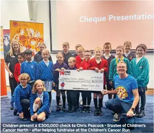  ?? ?? Children present a £300,000 check to Chris Peacock - trustee of Children’s Cancer North - after helping fundraise at the Children’s Cancer Run