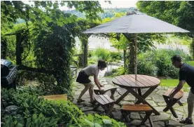  ??  ?? The owners of Auberge Majella arrange chairs in their garden at their inn in Lac-Mégantic.