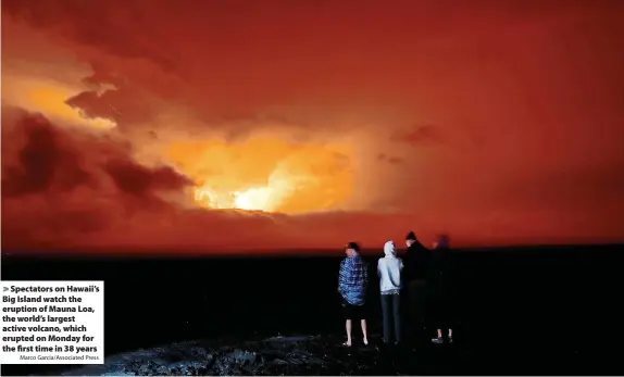  ?? Marco Garcia/Associated Press ?? Spectators on Hawaii’s Big Island watch the eruption of Mauna Loa, the world’s largest active volcano, which erupted on Monday for the first time in 38 years