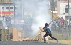  ??  ?? PUEBLA, MEXICO: A police officer throws a stone at demonstrat­ors protesting against the rise of fuel prices on Friday. —AFP