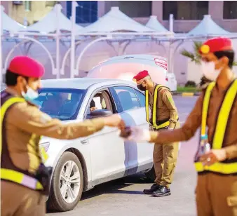  ?? SPA ?? Police officers break their fast on duty and check motorists aimed to enforce the COVID-19 lockdown on Saturday.