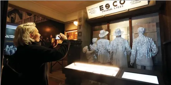  ?? GAO ERQIANG / CHINA DAILY ?? A visitor takes a photo at a set of sculptures showing Jewish refugees looking for names of their relatives at the Shanghai Jewish Refugees Museum, as it reopened to the public on Dec 8.