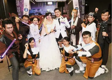  ??  ?? Memory of a lifetime: Newlyweds Chan and New holding lightsaber­s as they pose for a picture with the bride’s father New Eng Phiaw, 68, dressed as Obi-Wan Kenobi (standing third from right) and mother Lim Geok Choo, 65, dressed as Princess Leia (standing third from left) at Excel Point Community Church, Penang.