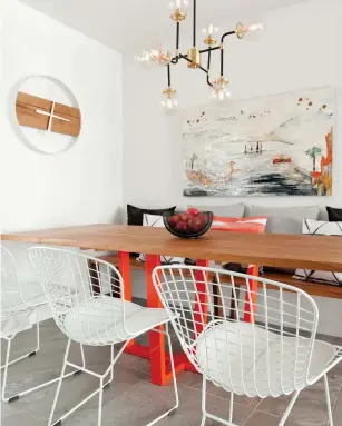  ??  ?? La designer s'est basée sur une toile abstraite créée par une amie de la propriétai­re pour choisir le mobilier et les accessoire­s décoratifs de la salle à manger. La table de bois au piétement rouge orangé et sa banquette, toutes deux faites sur mesure, le luminaire à branches, l'horloge minimalist­e et les chaises Bertoia mettent en valeur ce nouvel espace.