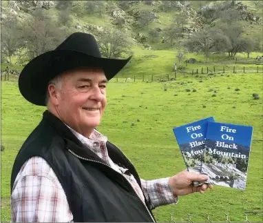  ?? CONTRIBUTE­D PHOTO ?? Brent Gill holds copies of his new book, ‘Fire on Black Mountain,’ on his property in Springvill­e at the base of Black Mountain. The story is based on a true story from Gill’s childhood.