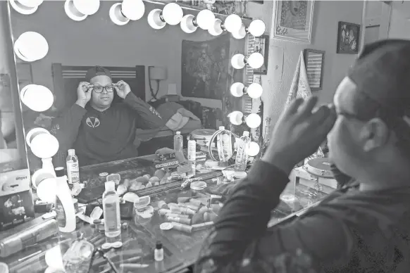  ?? PHOTOS BY JASPER COLT/USA TODAY ?? Kiba Walker, a drag queen who performs as Salem Moon, adjusts his glasses at the vanity in his bedroom in Fort Worth, Texas.