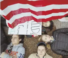  ?? AP PHOTOS ?? CALL TO ACTION: Protesters, above and right, hold signs and participat­e in a ‘die-in’ in front of the White House yesterday in Washington, D.C.