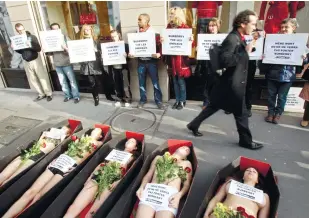  ??  ?? SCARE TACTICS. Peta demonstrat­ors lie in fake coffins, staging a protest against the use of fur by the British fashion house Burberry in Paris. Posters read, “Even dead, we will not wear Burberry.”