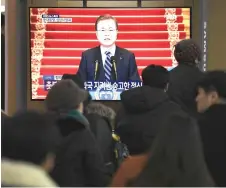  ?? — AFP photo ?? People watch a television screen broadcasti­ng live footage of Moon’s New Year speech, at a railway station in Seoul.