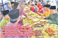  ??  ?? HIDANGAN TRADISI: Talib (kanan) bersama tetamu lain dihidangka­n dengan makanan tradisi pada Majlis Berlanggar Meja di Kampung Sebiew.