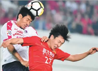  ?? LIU DAWEI / XINHUA ?? Zheng Long of Guangzhou Evergrande (front) and Eiichi Katayama of Cerezo Osaka contest a header during Tuesday’s Asian Champions League Group G match in Guangzhou. Evergrande won 3-1 to reach the last 16 as group winner.